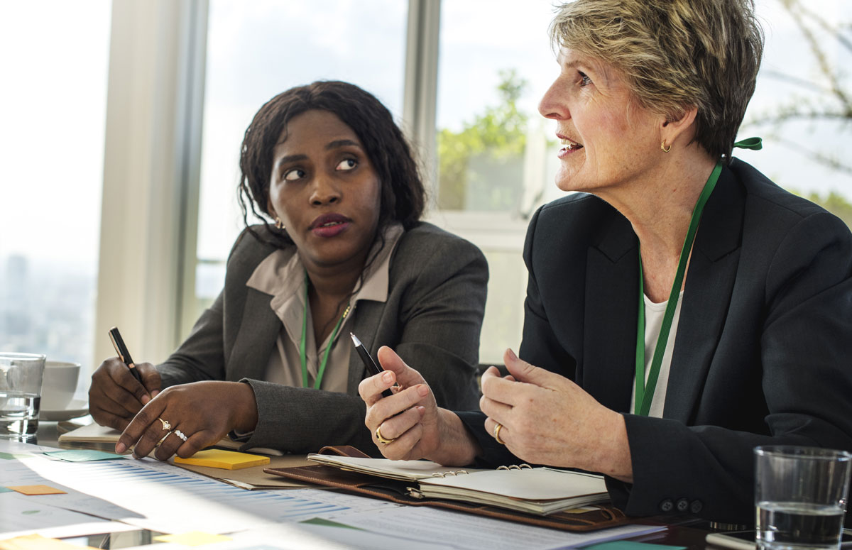 Two women at a conference table speaking