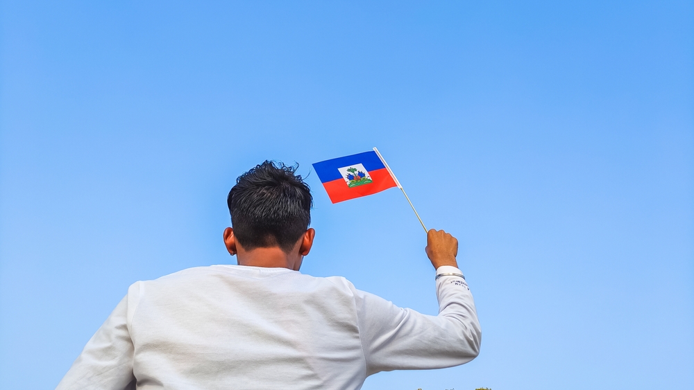Boy,Holding,Haiti,Flag,Against,Clear,Blue,Sky.,Man,Hand