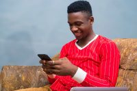 shutterstock_1318664792_sm Man using phone sitting on couch