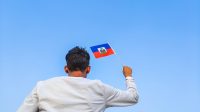 Boy,Holding,Haiti,Flag,Against,Clear,Blue,Sky.,Man,Hand