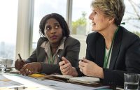 shutterstock_572008630 (2) Two women at a conference table speaking